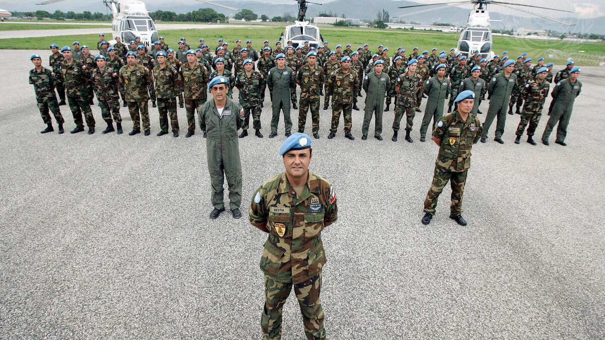 A battalion of Chilean soldiers in uniformed lined up in front of three helicopters. In front of the soldiers is their leader.