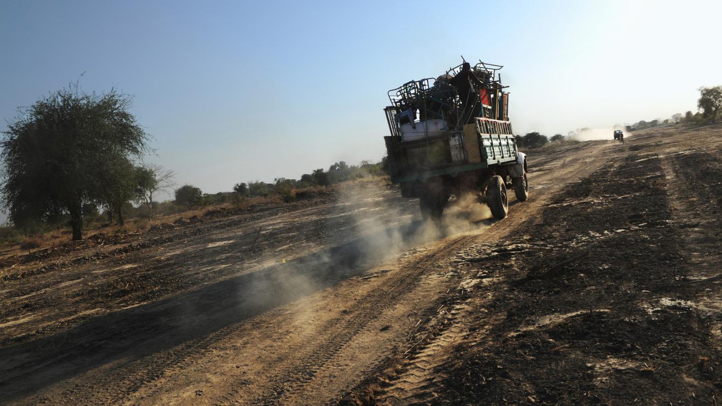 Open back lorry full of objects driving away on a dirt road
