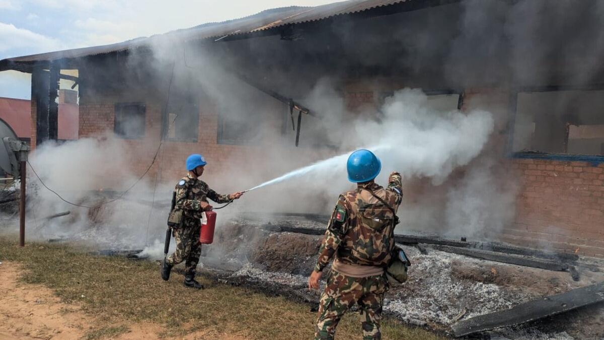 Deux casques bleus éteignent un incendie dans un bâtiment.
