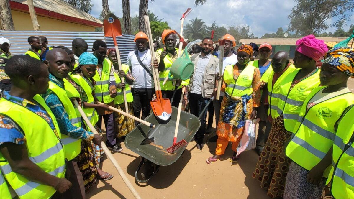 Former combatants, both men and women, receive tools suitable for farming in community fields.
