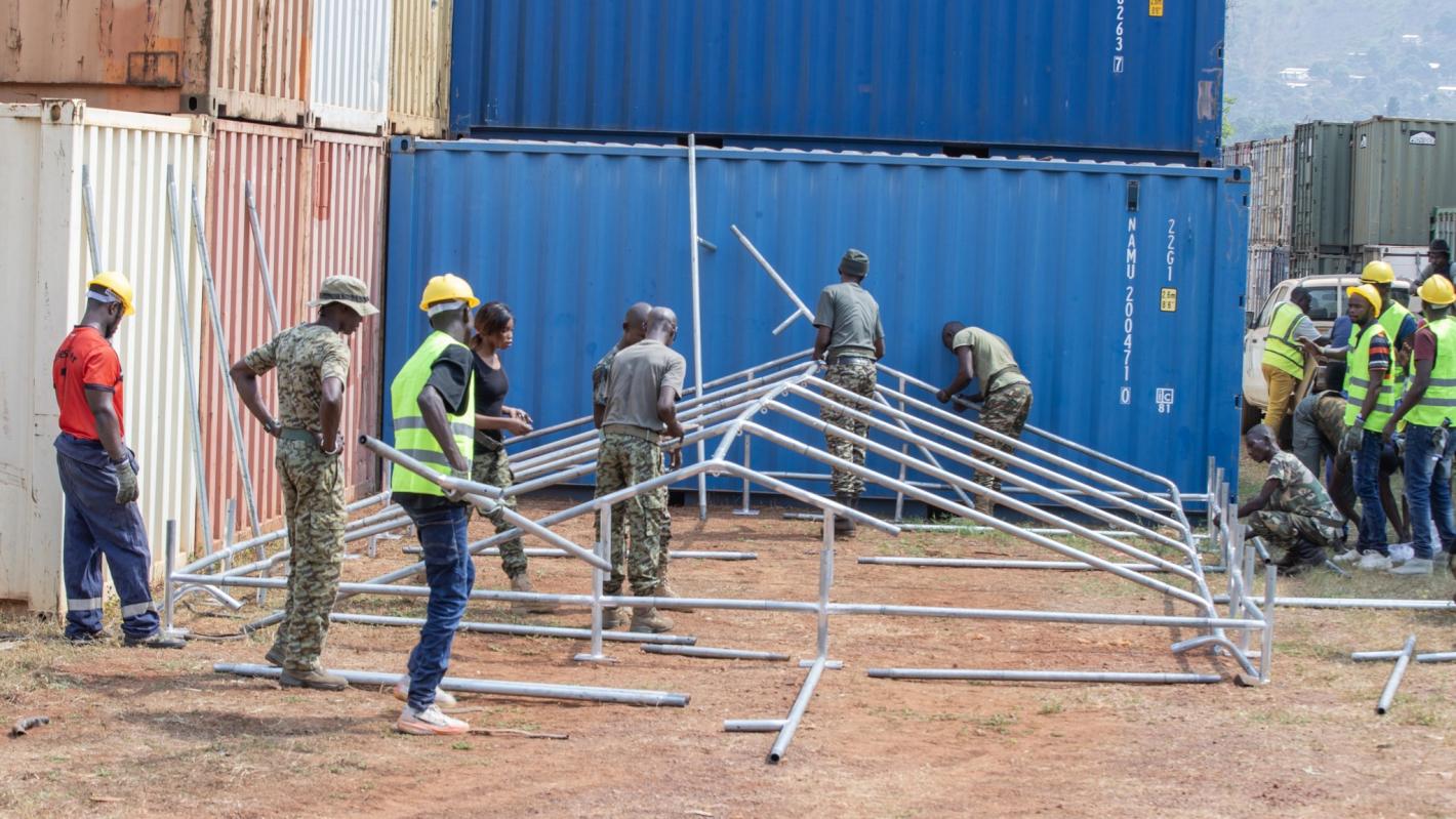 Many people working on a tent