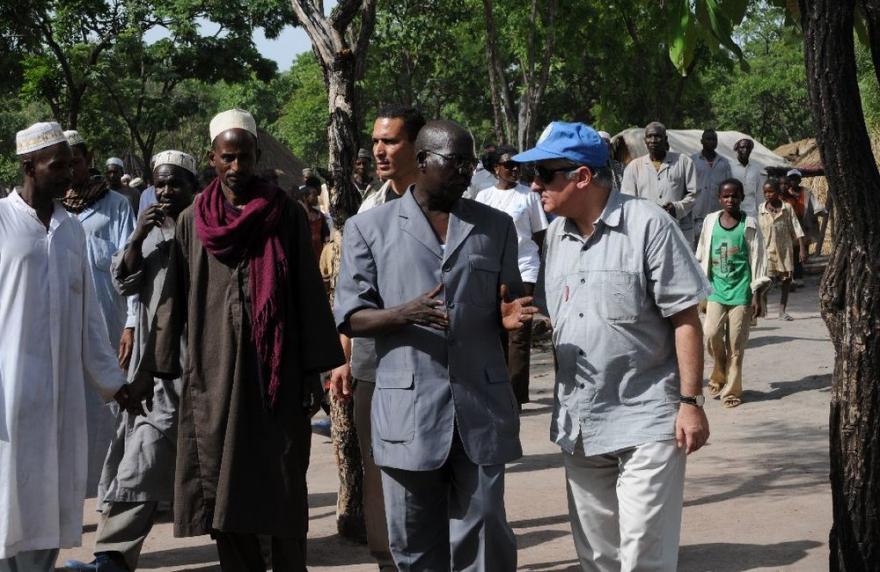 People walking in traditional clothes with the SRSG who is wearing a UN blue baseball cap
